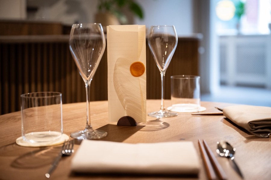 The menu sealed with an amber ginkgo wax seal, between two wine glasses