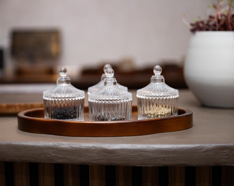 Cut-glass jars of peppercorns on a wooden tray